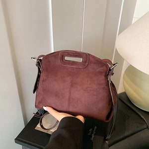 Brown suede crossbody bag with fringe detailing and a unique cutout handle design