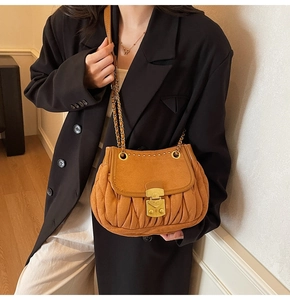 Close-up of yellow quilted crossbody bag with gold metal lock and chain strap on a model
