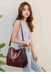 Detail of burgundy textured leather tote bag with silver zippers and dark brown straps