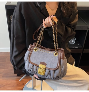 Detail of grey textured shoulder bag with golden twist lock and intricate pleated stitching