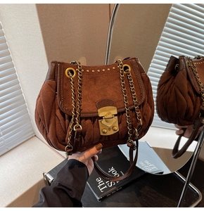 Close-up of brown quilted leather handbag with gold vintage lock and chain strap