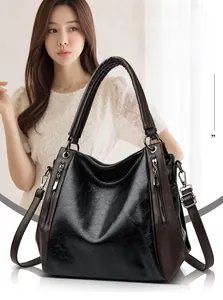 Detail of large tote bag with black lychee texture, brown contrast handles and metal zipper