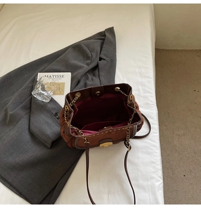 Top view of brown suede satchel with spacious interior pockets and gold chain strap