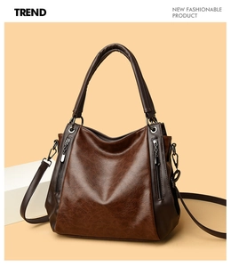 Close-up of vintage brown leather tote bag with decorative side zippers and metal hardware