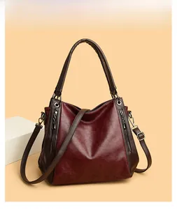 Detail of burgundy tote bag showing vintage oily leather texture and silver zipper accents