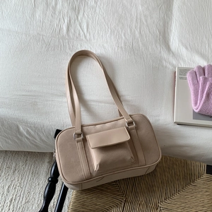 Vintage baguette shoulder bag in beige suede and leather on a woven chair