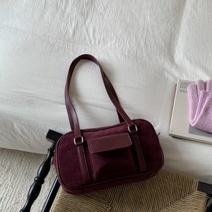 Retro burgundy baguette bag in suede and leather mix on a rustic background