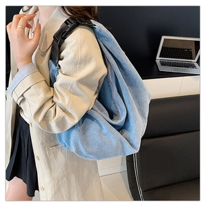 Detail of light blue denim hobo bag with black nylon strap and plastic buckle buckle