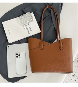 Vue de dessus d'un cabas en cuir grainé marron avec accessoires de bureau