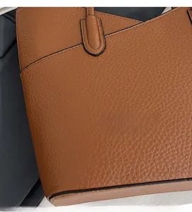 Détail du cuir marron à motif litchi avec coutures renforcées sur le sac à bandoulière