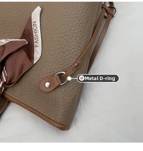 Detailaufnahme der braunen Kunstleder-Tasche mit D-Ring-Beschlägen und bedrucktem Seidentuch