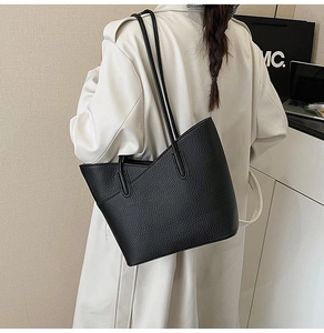 Détail d'un sac cabas classique en cuir noir texturé litchi porté à l'épaule avec coutures