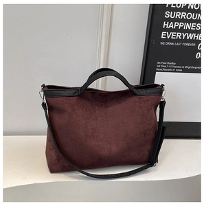 Detail of dark burgundy suede tote bag with black leather handles and adjustable strap