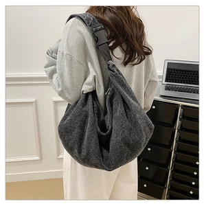 Detailed back view of a grey washed canvas crossbody bag with large buckle on model