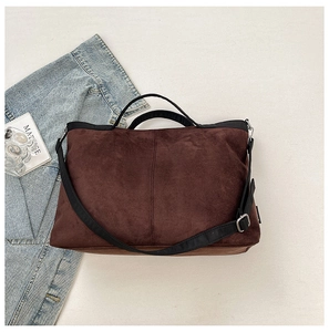 Detail view of brown suede tote bag with black strap and metallic hardware adjustments