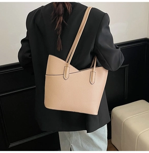 Gros plan d'un grand sac seau en cuir abricot avec bords ondulés porté par le mannequin