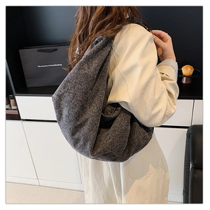 Detail of grey textured hobo bag showing large capacity and soft pleated fabric on shoulder