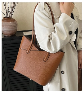 Gros plan d'un sac cabas en cuir marron porté avec un trench-coat beige