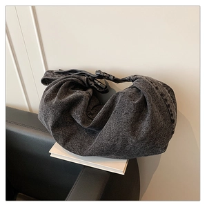 Detail of dark denim crossbody bag featuring pleated design and adjustable buckle strap