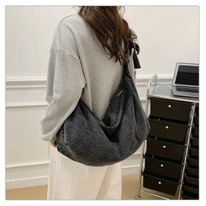 Detailed view of spacious dark grey denim crossbody bag worn by model in home setting