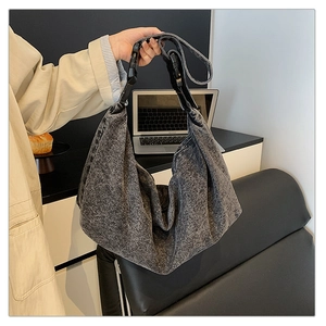 Detail of charcoal grey washed denim crossbody bag with adjustable wide strap and buckle