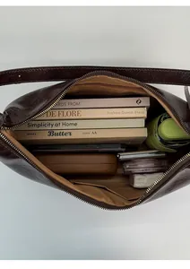 Top view of retro brown shoulder bag showing spacious interior with books and cosmetics