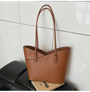 Gros plan d'un cabas en cuir marron avec ouverture en V asymétrique et texture grainée