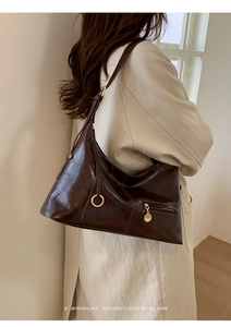 Detail of dark brown oily leather hobo bag with adjustable strap and gold hardware