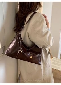 Detail of hobo bag in dark coffee oil wax leather with retro pleated texture and charms