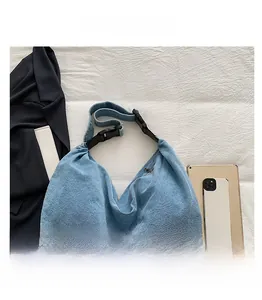 Close-up of light blue denim crescent shoulder bag with zipper and adjustable strap
