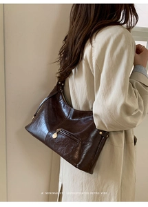 Close-up of retro dark brown wax leather underarm bag with gold metal zipper detail