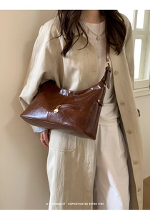 Detail of vintage dark brown faux oil wax leather shoulder bag with gold hardware accent