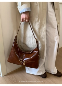 Detail of retro dark brown leather tote with gold hardware and minimalist zipper pull