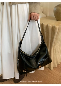 Detail of black glossy leather hobo bag featuring premium gold zipper and metal hardware