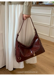 Close-up of retro burgundy leather tote bag with gold hardware and zipper details