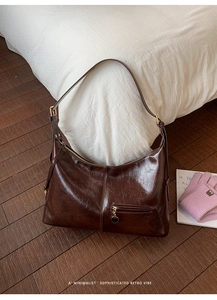 Detailed macro view of dark brown glossy leather texture and gold hardware on hobo bag