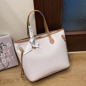 Detail der cremefarbenen Shopper-Tasche mit braunem Rand und modischem Seidenschal