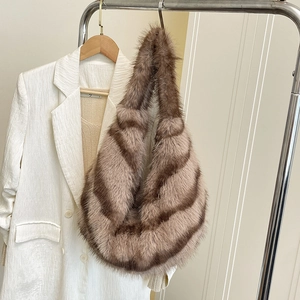 Plush faux fur shoulder bag with brown striped pattern on a clothing rack