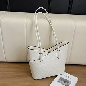 Grand sac à main blanc en cuir grainé avec design en V posé sur une table en bois