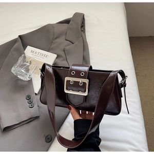 Detail of dark brown patent leather baguette bag with a large metallic buckle decoration