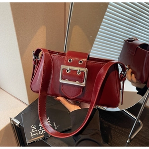 Detail of burgundy leather shoulder bag featuring a large silver square metal buckle