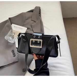 Detail of a shiny black minimalist underarm bag with a vintage silver square buckle buckle
