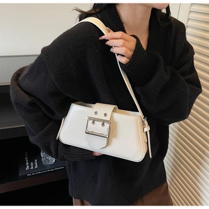 Detail of a minimalist cream baguette bag with silver buckle and wide shoulder strap