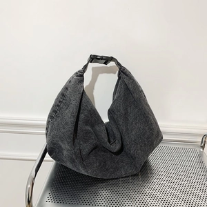 Minimalist grey washed denim hobo bag with adjustable buckle on a metallic cart