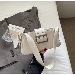 Detail of cream white rectangular shoulder bag with large silver buckle and wide strap