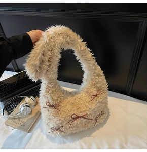 Detailed close-up of plush faux fur shoulder bag with burgundy bows and gold bells