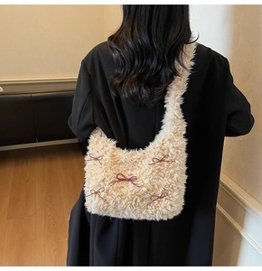 Detail of plush cream underarm bag with dark brown bows and gold metal accents