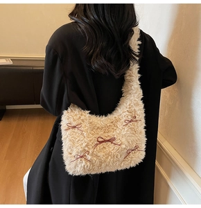 Detail of soft cream plush shoulder bag with delicate burgundy ribbon bow accents