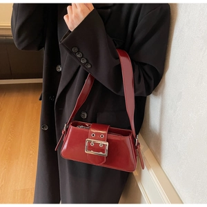Close-up of retro burgundy glossy leather underarm bag with a bold silver metal buckle
