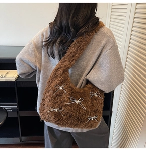 Close-up of brown plush shoulder bag featuring silver bows and heart charms on a sweater